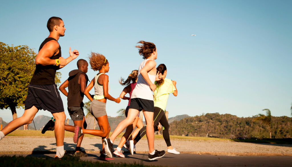 Um grupo de corredores juntos ao ar livre. Reforçando um dos benefícios da corrida no seu corpo como a sociabilidade e criação de conexões.