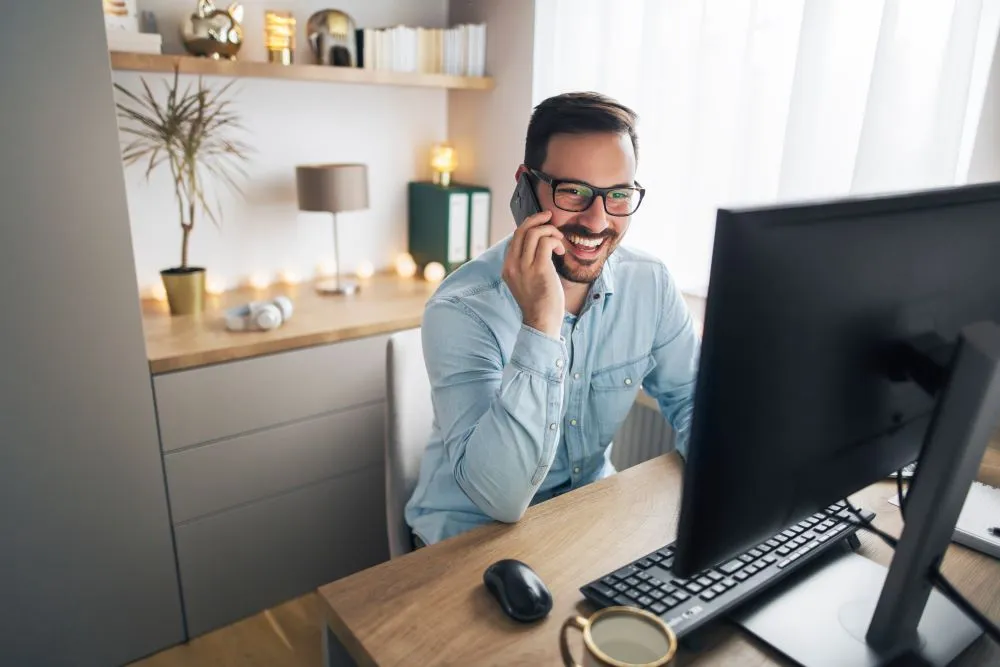 Imagem de um homem trabalhando e demonstrando como organizar seu ambiente de trabalho para a saúde mental com a luz natural