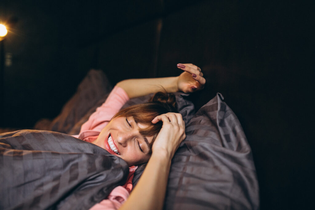 Imagem demonstrando uma mulher acordando exemplificando como dormir bem é um dos segredos de como se sentir mais jovem